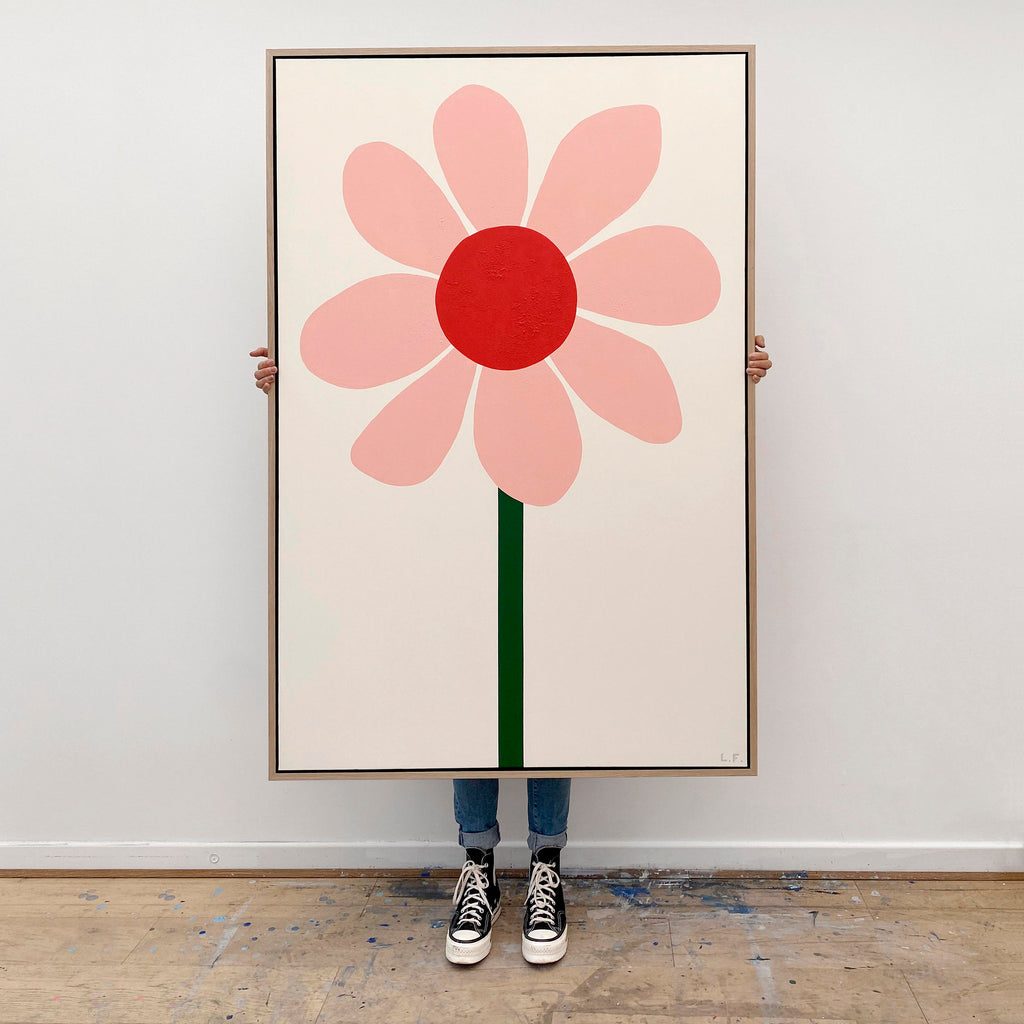 Woman sitting on table beside a painting of a giant apple